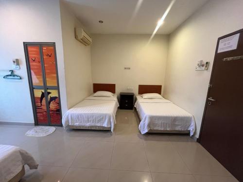 a room with two beds and a door in it at Hotel O Kledang Menglembu in Ipoh