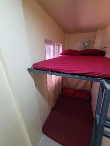 a small room with a bunk bed with red pillows at BenRitz Transient House in Urdaneta