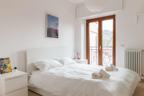 a white bedroom with a bed with towels on it at Wellness Holiday Home in Brunate