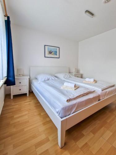 a bedroom with a white bed and a wooden floor at Silbermöwe in Greetsiel