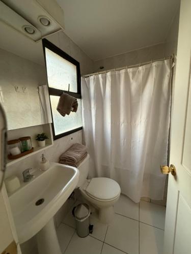 a white bathroom with a toilet and a sink at Depto LAS CONDES-EST ESPAÑOL in Santiago
