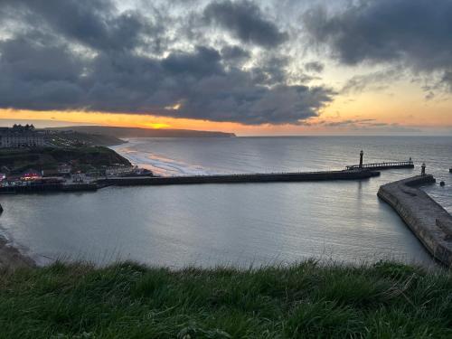 a pier in the water with a sunset in the background at Saltwick Cottage in Whitby