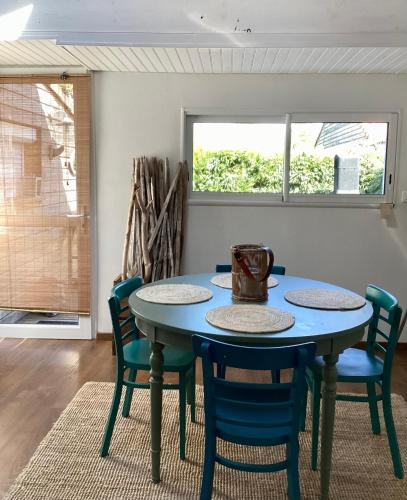 a blue table and chairs in a room with a window at La cabane du littoral in La Teste-de-Buch