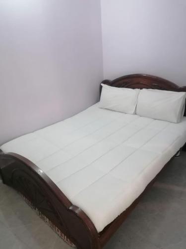 a bed with a wooden headboard and two pillows at Mount Murree Hotel in Murree