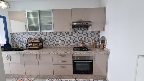 a kitchen with white cabinets and a stove top oven at Appartement luxueux - Piscines, Plage 300m, Résidence fermée in Martil