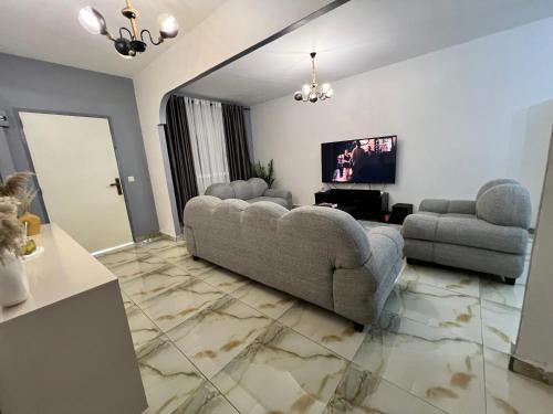 a living room with two couches and a flat screen tv at Sweet House Residence in Douala
