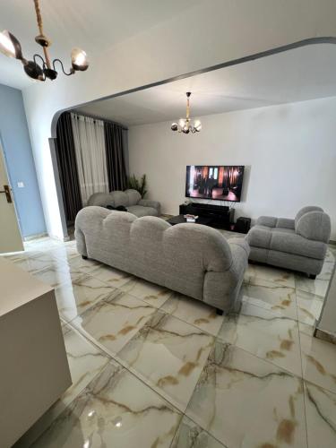 a large living room with a couch and a television at Sweet House Residence in Douala