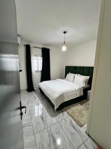 a bedroom with a bed with white sheets and black curtains at Sweet House Residence in Douala