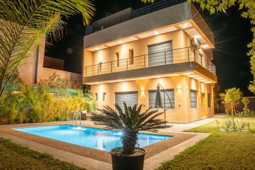 a villa with a swimming pool in front of a house at Villa Park Marrakech in El Aggada
