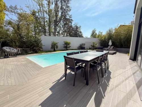 eine Terrasse mit Tisch und Stühlen neben einem Pool in der Unterkunft Villa haut de gamme avec Piscine, Bar et Cinéma in Pierre-Levée