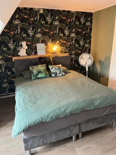 a bedroom with a bed with a green comforter at Slapen bij Bartje in Assen