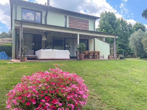 une maison avec des fleurs roses dans la cour dans l'établissement Casale Geos, à Capannori