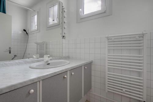 une salle de bain blanche avec un lavabo et une douche dans l'établissement 20m de la mer - Terrasse - Appartement pour 6, à Pornic