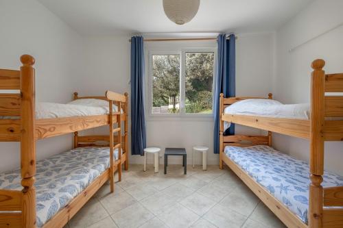 une chambre avec trois lits superposés et une fenêtre dans l'établissement 20m de la mer - Terrasse - Appartement pour 6, à Pornic