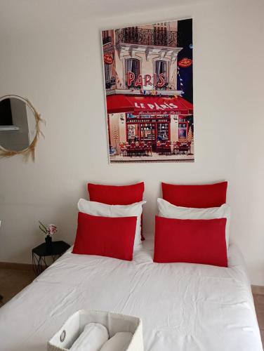 - un lit avec des oreillers rouges et une affiche murale dans l'établissement B201 Studio 10 min DisneyLand Paris, à Montévrain