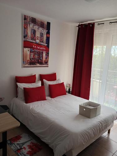 a bed with red pillows and a box on it at B201 Studio 10 min DisneyLand Paris in Montévrain