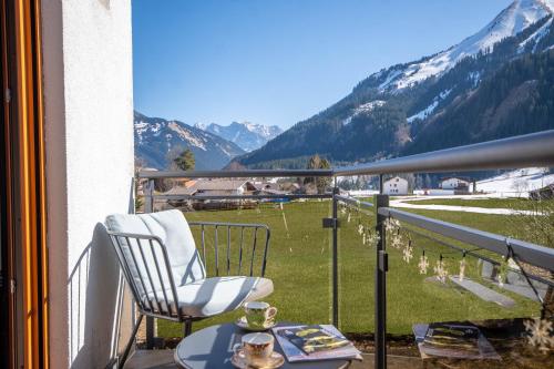 a chair and a table on a balcony with mountains at Appartement Alpenliebe in Bichlbach