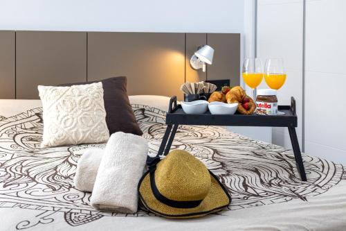 Laguna Beach Villa Veintidos في توريفايجا: صينية طعام على سرير مع أكواب من عصير البرتقال