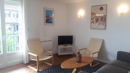 un salon avec un canapé, des chaises et une télévision dans l'établissement Appartement T3-4 meublé Toulouse Soupetard, à Toulouse