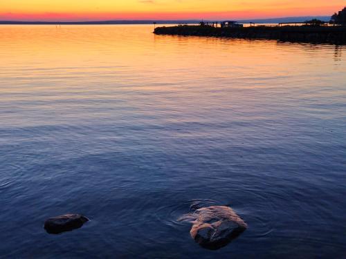 two rocks in the water with a sunset in the background at Magisch berghuisje met uitzicht op Nationaal Park Fulufjället in Sörsjön