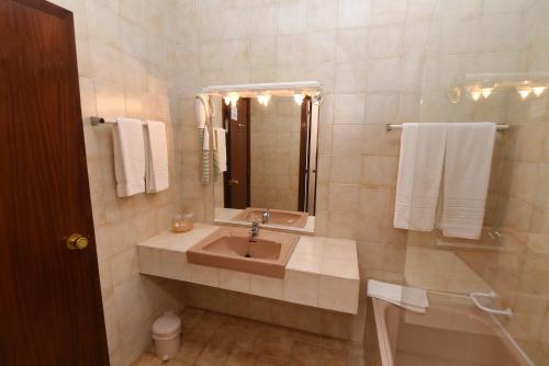 a bathroom with a sink and a mirror and towels at Praia da Lota Resort – Beachfront Hotel in Manta Rota