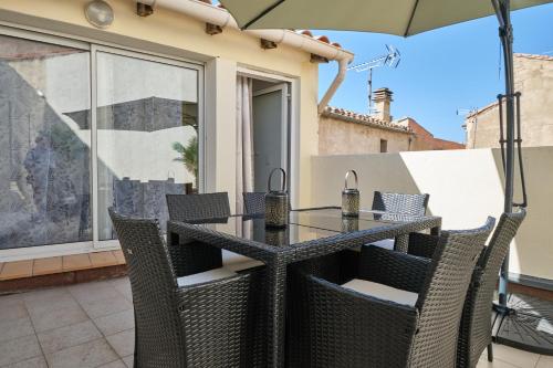 une table avec des chaises et un parasol sur une terrasse dans l'établissement Spacieux Appartement Climatisé au centre-ville de Narbonne, à Narbonne