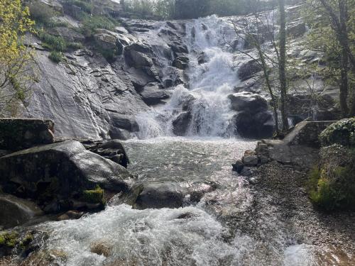 a waterfall on the side of a river with rocks at Mar de Nubes Piornal 3 in Piornal