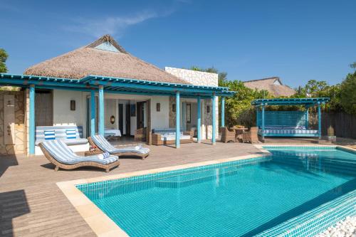a swimming pool with two lounge chairs next to a house at Banana Island Resort Doha by Anantara in Doha