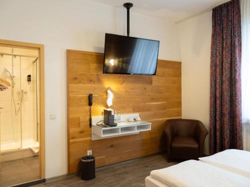 a hotel room with a bed and a tv on the wall at DONAUHOTEL Ingolstadt in Ingolstadt