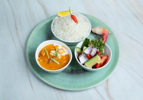 a green plate with rice and a bowl of food at SOALTEE Hotel by Trip Inn Frankfurt Messe Tagungshotel in Frankfurt/Main