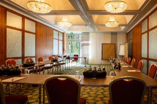 a conference room with long tables and chairs and chandeliers at SOALTEE Hotel by Trip Inn Frankfurt Messe Tagungshotel in Frankfurt/Main