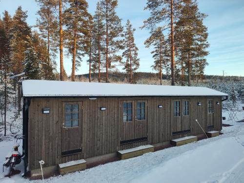 a large wooden building in the snow with a motorcycle at Magisch berghuisje met uitzicht op Nationaal Park Fulufjället in Sörsjön