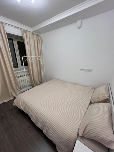 a white bedroom with a bed and a window at Светлая 2 спальная квартира в историческом центре Астаны in Astana