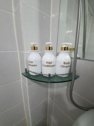 a shelf in a bathroom with four bottles on it at Residence Stay Avenu in Ulsan