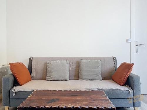 - un canapé gris avec des oreillers orange dans le salon dans l'établissement La Boulangerie Parisienne - Central Rive Gauche, à Paris