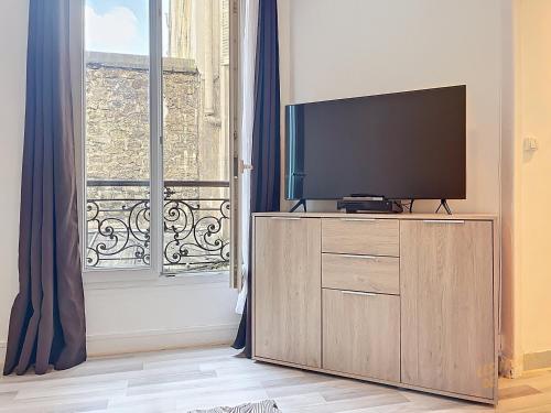 une télévision sur une commode devant une fenêtre dans l'établissement La Boulangerie Parisienne - Central Rive Gauche, à Paris