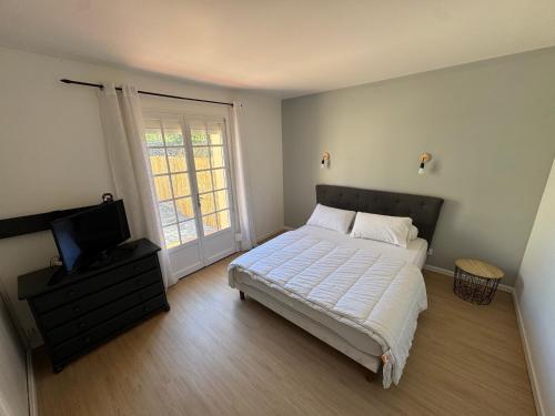 une chambre avec un lit et une télévision à écran plat dans l'établissement Villa Manaha - 6pers - clim - proche plage, à Lapalme