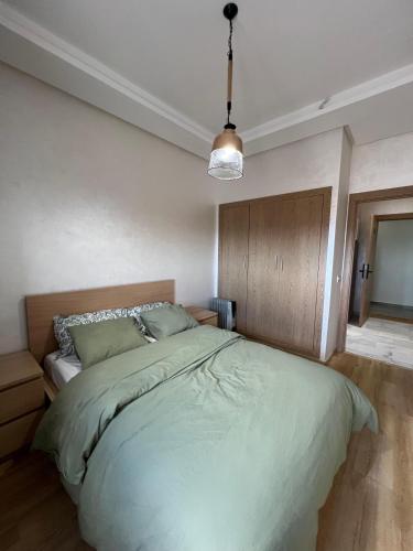 a bedroom with a large bed and a pendant light at Ocean park zenata in Aïn Harrouda