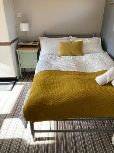 a bedroom with a bed with a yellow blanket at Home for one! in Midford