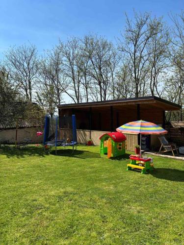 un patio con una casa con sombrilla y parque infantil en Petlov konak, en Mala Remeta