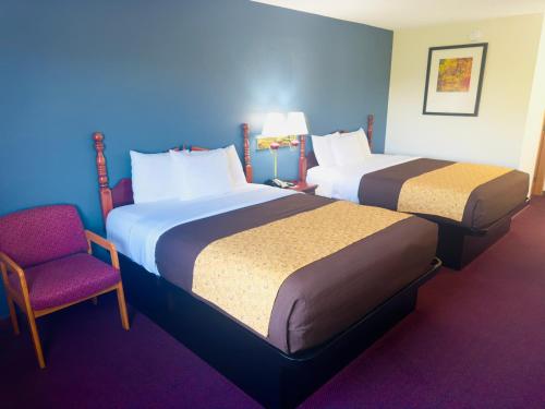 a hotel room with two beds and a chair at Scenic Hills Inn in Branson