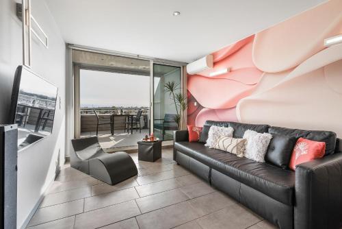 un salon avec un canapé noir et un balcon dans l'établissement Village Naturiste R4N - Sixty9 Port Ambonne, au Cap d'Agde