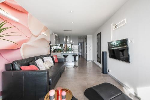 a living room with a black couch and a tv at Village Naturiste R4N - Sixty9 Port Ambonne in Cap d'Agde