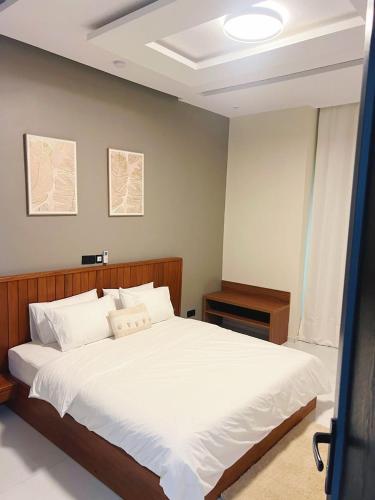 een slaapkamer met een groot bed met witte lakens bij Les Résidences KYM in Yamoussoukro