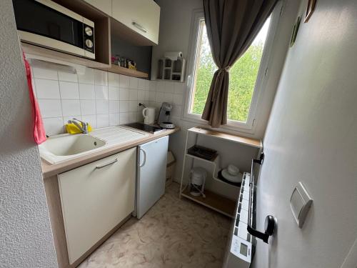 une petite cuisine avec un évier et une fenêtre dans l'établissement Studio T1 piscine chauffée parking gratuit les hauts dhonfleur, à Équemauville