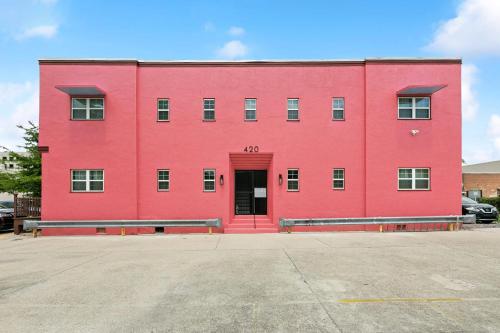 a red building with a red door in a parking lot at StayAE Downtown - 1BR Apartment, Second Floor in Baton Rouge