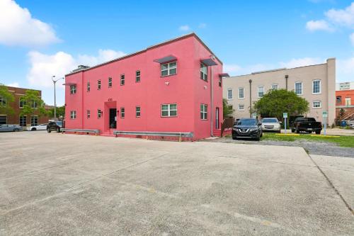 a red building in a parking lot with cars parked at StayAE Downtown - 1BR Apartment, Second Floor in Baton Rouge