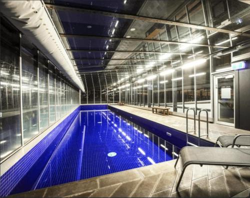 a large swimming pool with blue water in a building at Riverside Near Crown with carpark in Melbourne