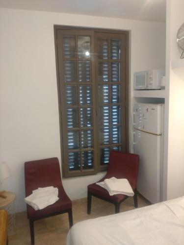 une chambre avec deux chaises et un réfrigérateur et une fenêtre dans l'établissement Couche-tard, au Bourget