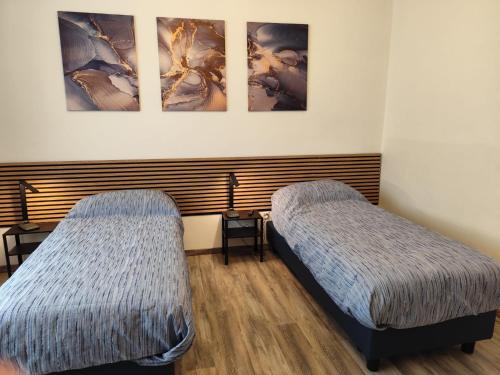 two beds in a room with paintings on the wall at Biella Living in Biella